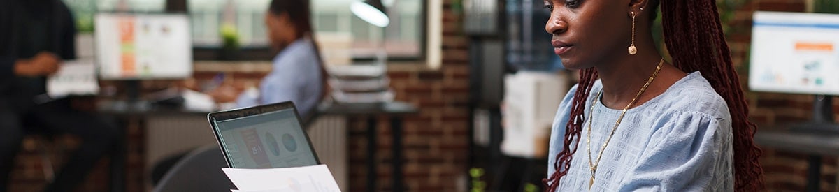 Bir kadın ofiste masa başında oturmuş evrakları inceliyor